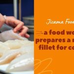 a food worker prepares a raw fish fillet for cooking